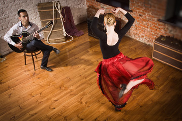 Obraz premium Young woman dancing flamenco and a man playing the guitar