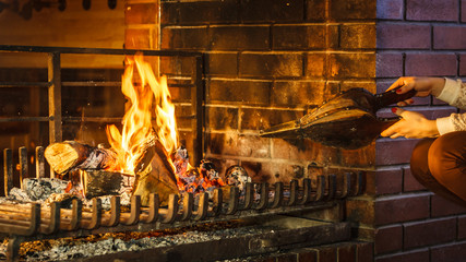 Closeup hands fireplace making fire with bellows.