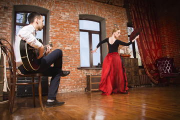 Naklejka na ściany i meble Young woman dancing flamenco and a man playing the guitar