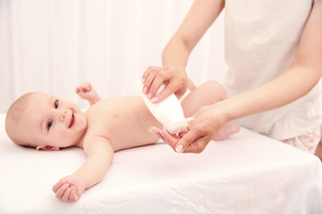 Mother hands changing diaper to little baby in room