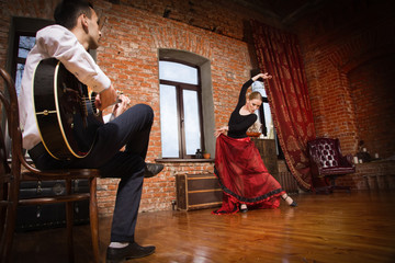 Naklejka premium Young woman dancing flamenco and a man playing the guitar