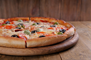 Pizza with cheese on board and wooden table background