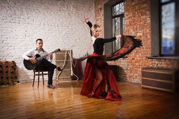 Fototapeta premium Young woman dancing flamenco and a man playing the guitar