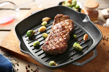 Grilled steak with garlic and Brussels sprouts on grill pan, closeup