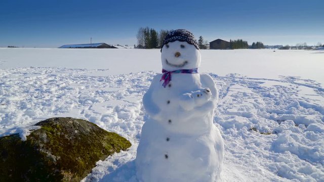 The cute snowman with bonnet on the head. This snowman is made from thick snow during the winter season