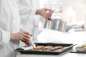 Obraz na płótnie Canvas Chefs decorating cookies with chocolate.