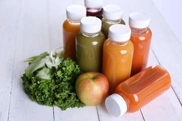 Diet concept: vegetable juices in bottles on wooden background