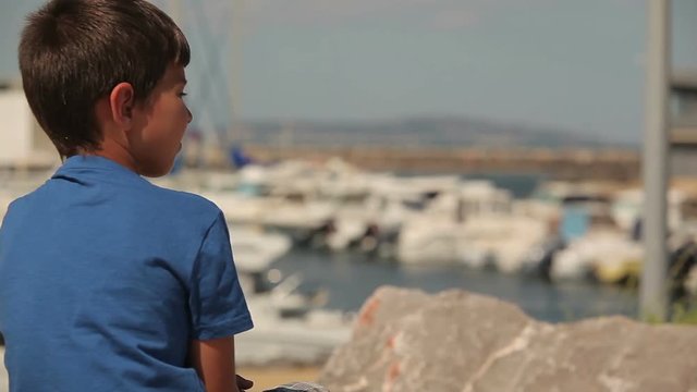 boy looks at a yacht on the sea