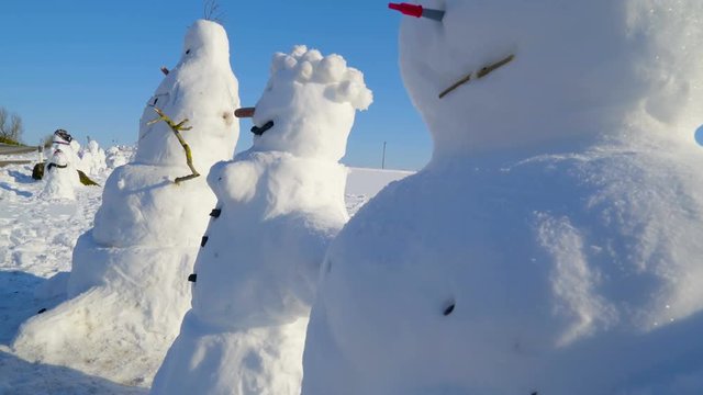 The three snowman in a side view image. This snowman are figures made by children using a snow
