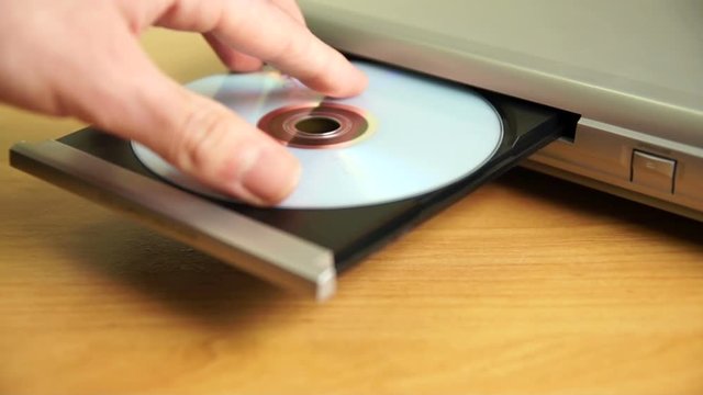 A hand inserts a DVD disc into a player.