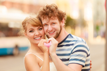 Couple on city street making heart shape by hands