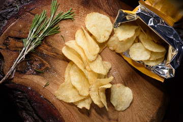 Heap of potato chips with rosemary over wooden background. View from above.