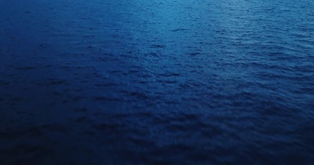 Flying over ocean at dusk, aerial view flying over water with dramatic clouds - Powered by Adobe