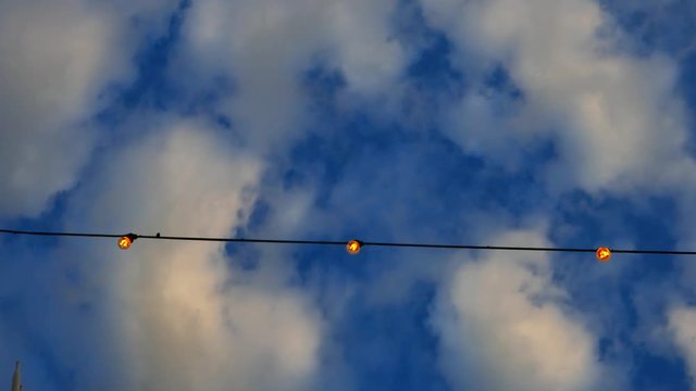 STOCKHOLM, SWEDEN, MAY 2016: low angel shot of outdoor string lights with cloud backgrounds