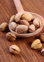 Pistachio nuts with spoon on wooden table, healthy eating