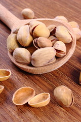 Pistachio nuts with spoon on wooden table, healthy eating