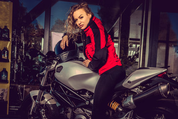 Blond female posing near motorcycle.