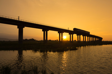 Fototapeta na wymiar A train is crossing bridge at Pa Sak Jolasid Dam, Thailand in sunset time