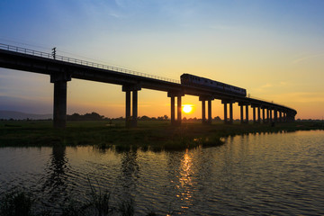 A train is crossing bridge at  Pa Sak Jolasid Dam, Thailand in sunset time