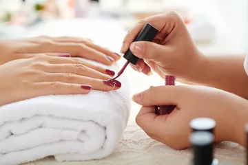 Deurstickers Manicure Zijaanzicht van manicure die marsala nagellak aanbrengt