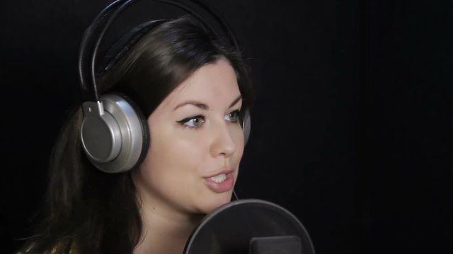 girl in the studio reading a text and sings in the headphones
