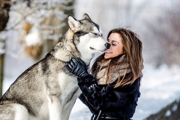 Young girl playing with a dog in the snow in the winter