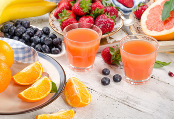 Citrus juice, fruits and berries on wooden background. Healthy e