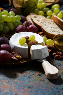 Camembert cheese, fruits and honey on dark background, vertical