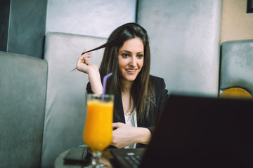 Young attractive business woman sitting in modern cafe restaurant and looking on her notebook. 