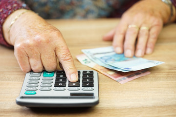 Older woman is using calculator to calculate all expenses
