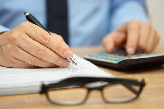 closeup of businessman reviewing financial document and calculat