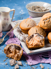 Lavender muffins with ingredients - lavender syrup, milk and lavender flowers on blue textured background. Vertical image. Closeup