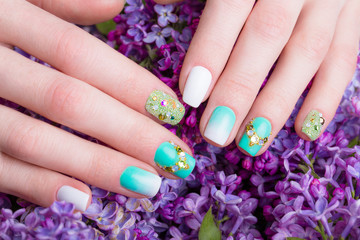 Beautiful turquoise manicure with crystals on female hand. Close-up.