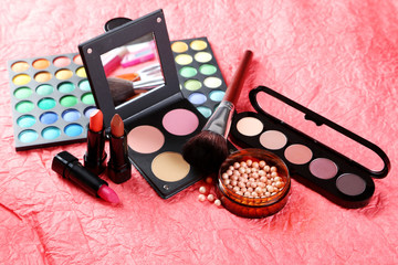 Obraz na płótnie Canvas Makeup brush and cosmetics on a red background