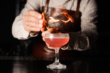 The bartender makes flame above cocktail