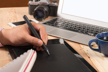 
Photographer drawing and retouching image on laptop computer, using a digital tablet and stylus...