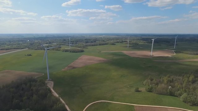 Aerial moving view: Several wind turbine with sky background road with traffic