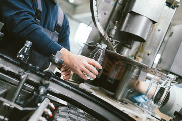 Serious manual worker doing his job on factory production line for water purification and bottling.