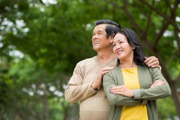 Married mature Asian couple standing in the park