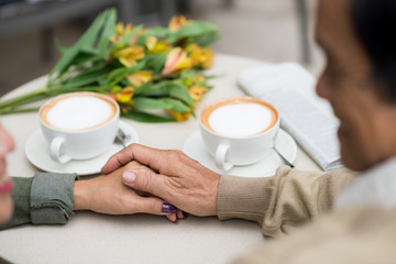 Senior man touching hand of his wife when they sitting in cafe