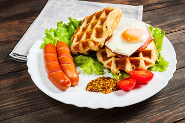 Belgian waffle with egg and sausage on wood table