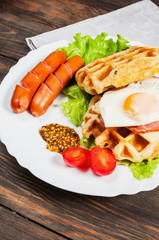 Belgian waffle with egg and sausage on wood table