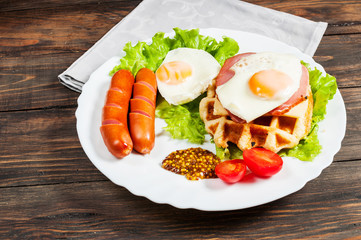 Belgian waffle with egg and sausage on wood table