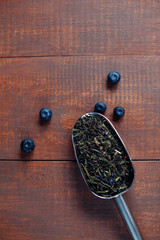 assortment of dry tea in spoons with blueberry on wooden backgro