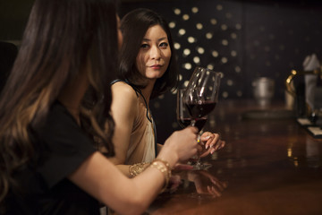 Two young women are drinking wine at the bar of the counter