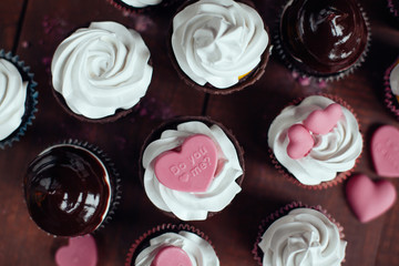 a lot of cupcakes with pink little candy hearts on topping.top v
