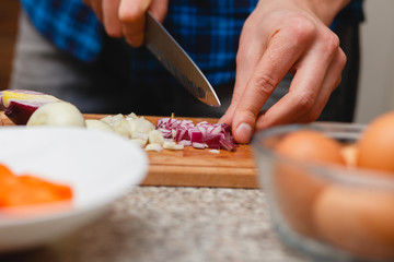 Obraz premium cooking, food and home concept - close up of male hand cutting vegetables on cutting board at home