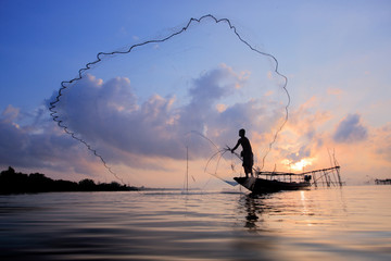 Fishermen on boat fishing with a fishnet,the old traditional equipment of Thai fishery.Silhouette scene in Pak Pra Village, Pattalung province, Thailand.