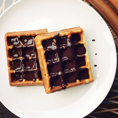 Vienna Waffles with chocolate topping. Retro toned photo. View from the Top. Delicious dessert. White plate with Chocolate covered Wafers. Aged photo. Delicious dessert.