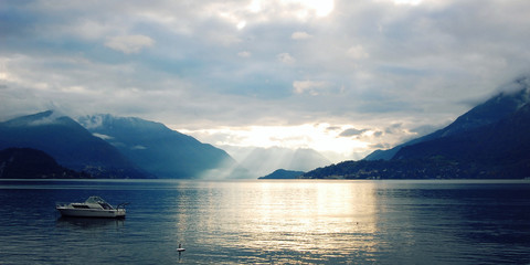 Boat on Lake Como at the sunset. Silver linings in Lake Como at the sunset. Retro style photo. Sunset view of the lake in Lombardy. Varenna, Lake Como, Italy.